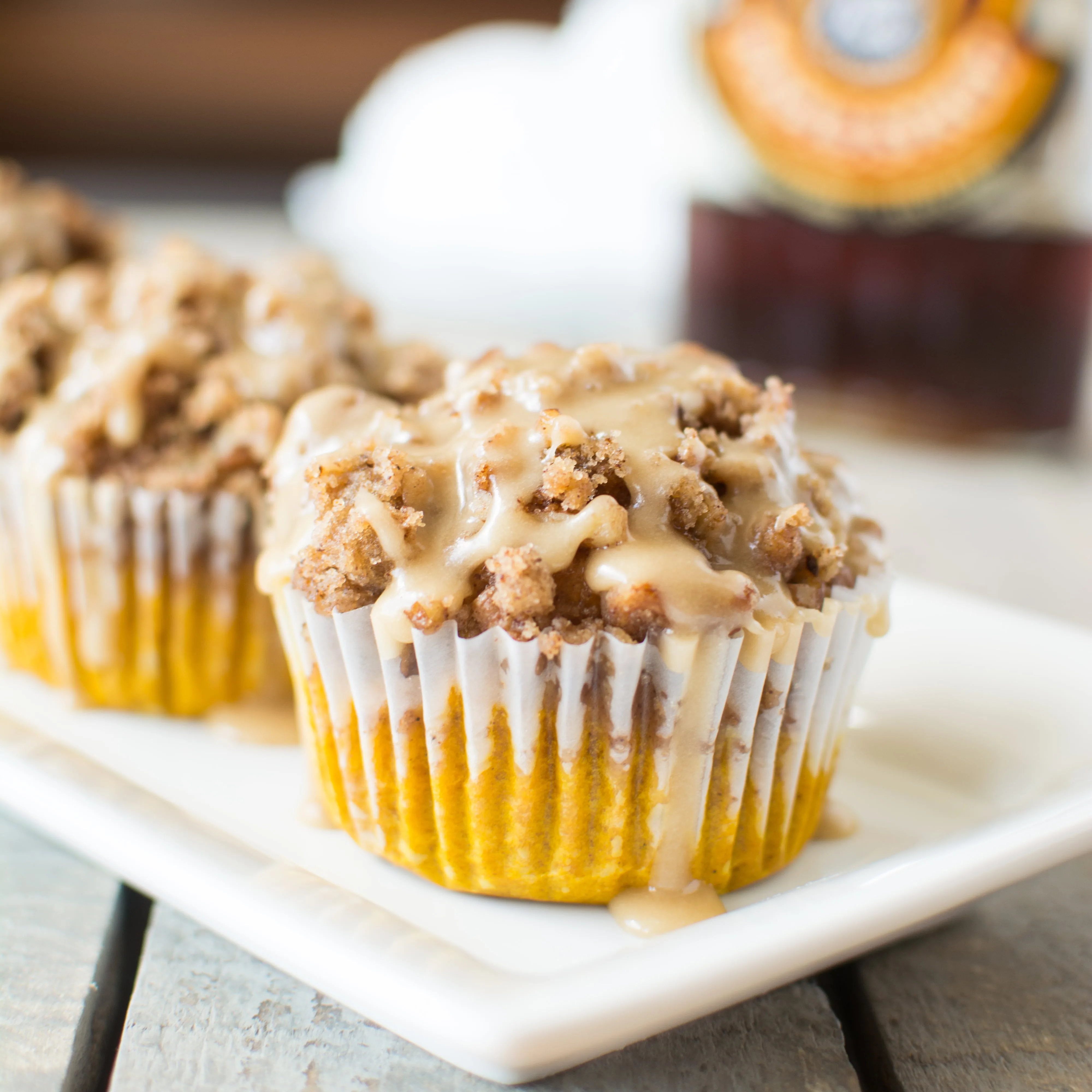 Moist and fluffy muffins loaded with pumpkin and autumn spices, piled high with a buttery streusel crumble, and drizzled with a thick maple glaze!