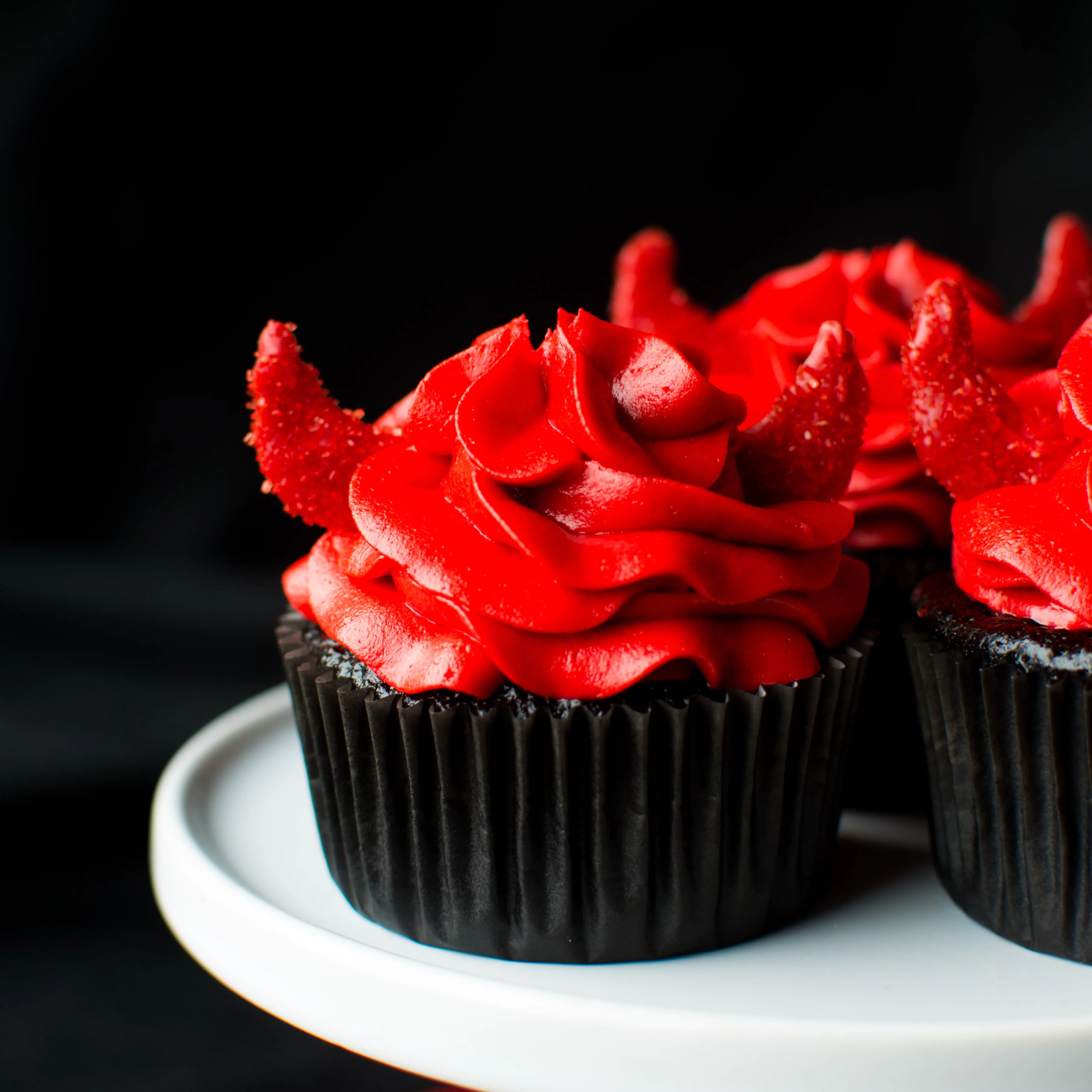 Super moist and intensely dark chocolate devil's food cupcakes with a kick of cinnamon, chili powder, and cayenne, topped with a red velvet buttercream and darling little devil horns!