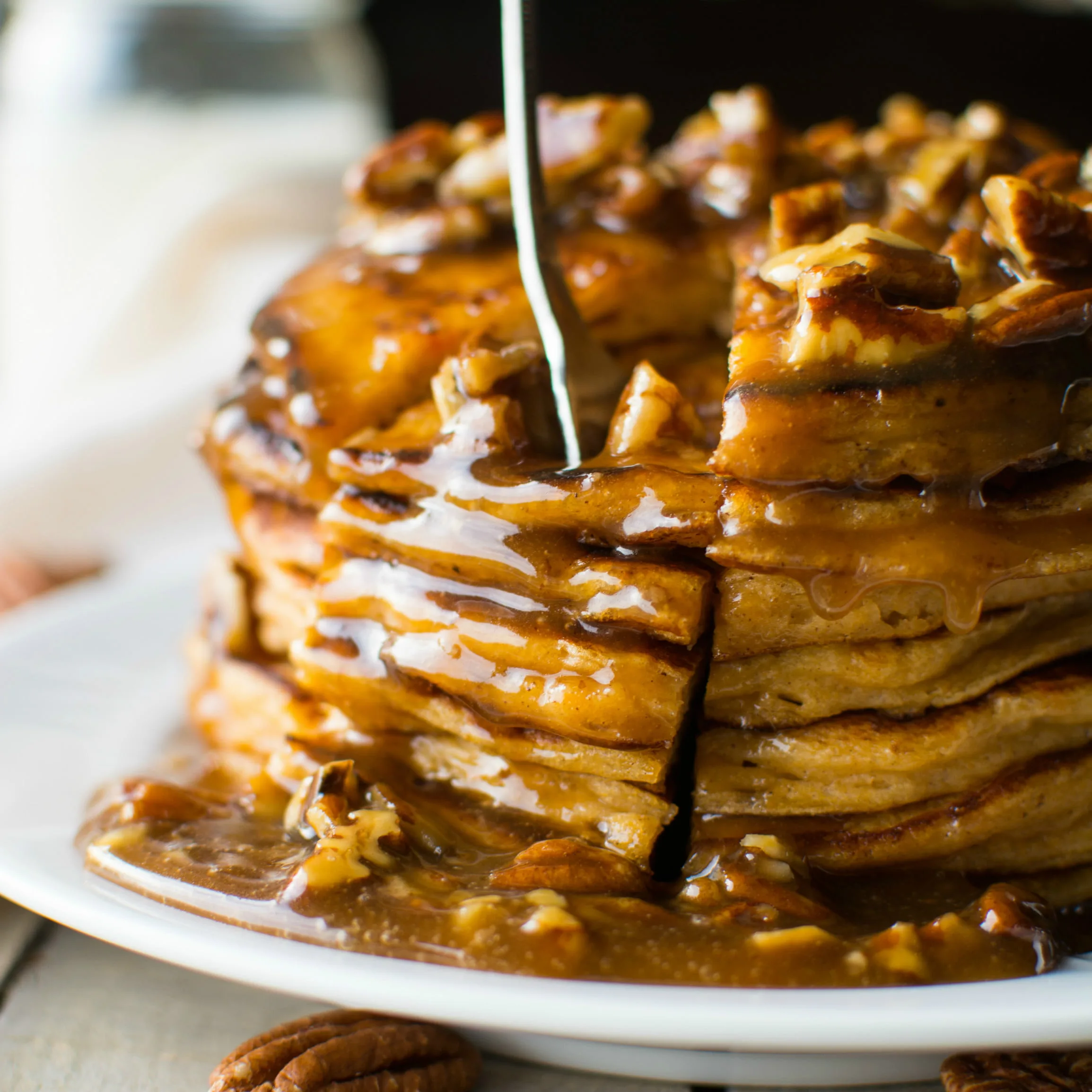 Fluffy sweet potato pancakes stacked high and topped with a to-die-for pecan praline syrup!