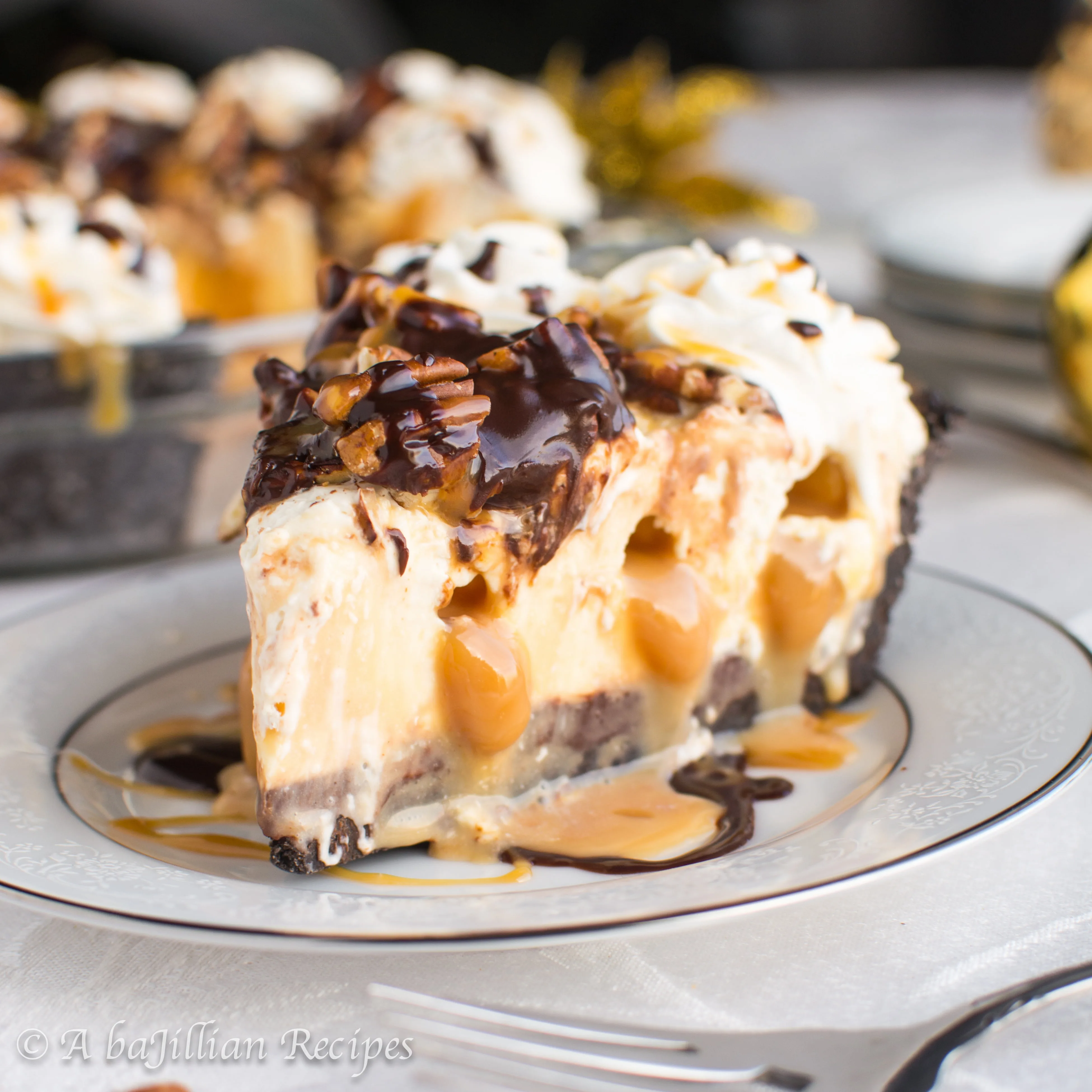 An Oreo cookie crust filled with a layer of dark chocolate ganache, a no-bake cheesecake-like filling INJECTED with pockets of caramel, and topped with caramel, ganache, and chopped pecans!