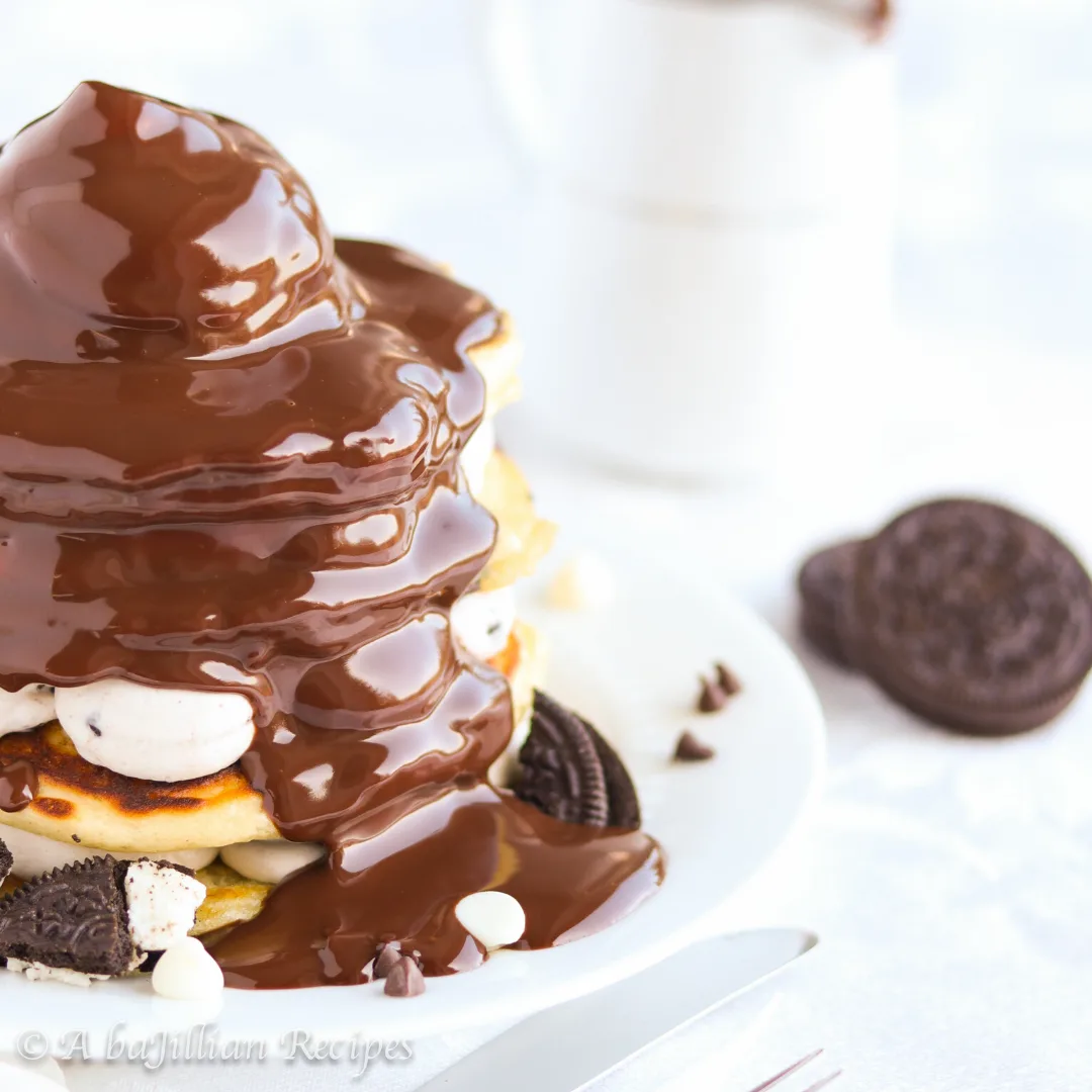 Fluffy pancakes speckled with Oreos, layered with cookies n' creme cheesecake filling, and topped with rich chocolate ganache!