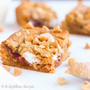 Peanut butter blondies stuffed with marshmallow fluff and strawberry jam, topped with peanuts and peanut butter chips!
