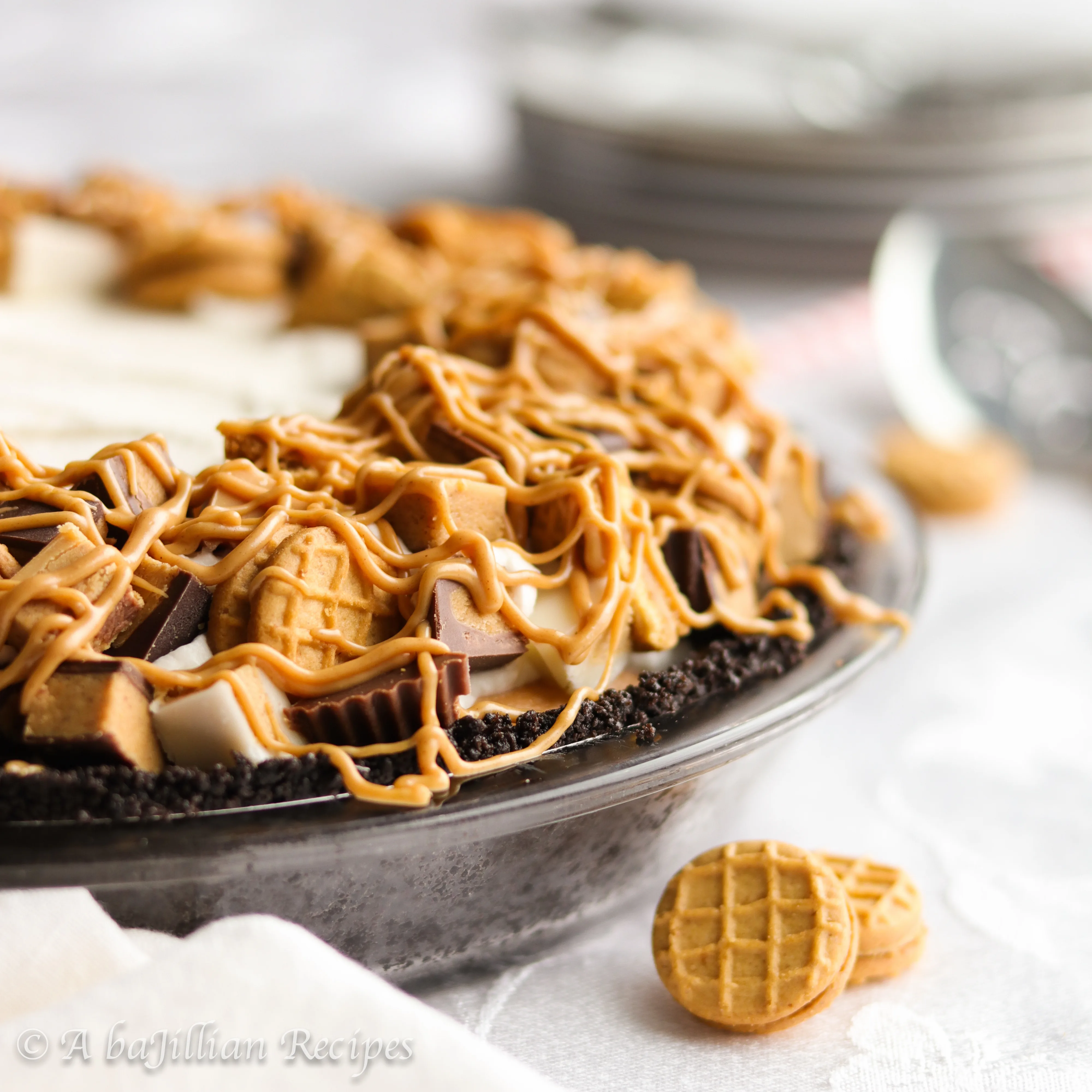 This no-bake pie features a Nutter Butter cookie truffle filling, peanut butterscotch cream filling, fluffy whipped cream, a generous crown of Reese's Cups, and a luscious peanut butter drizzle!