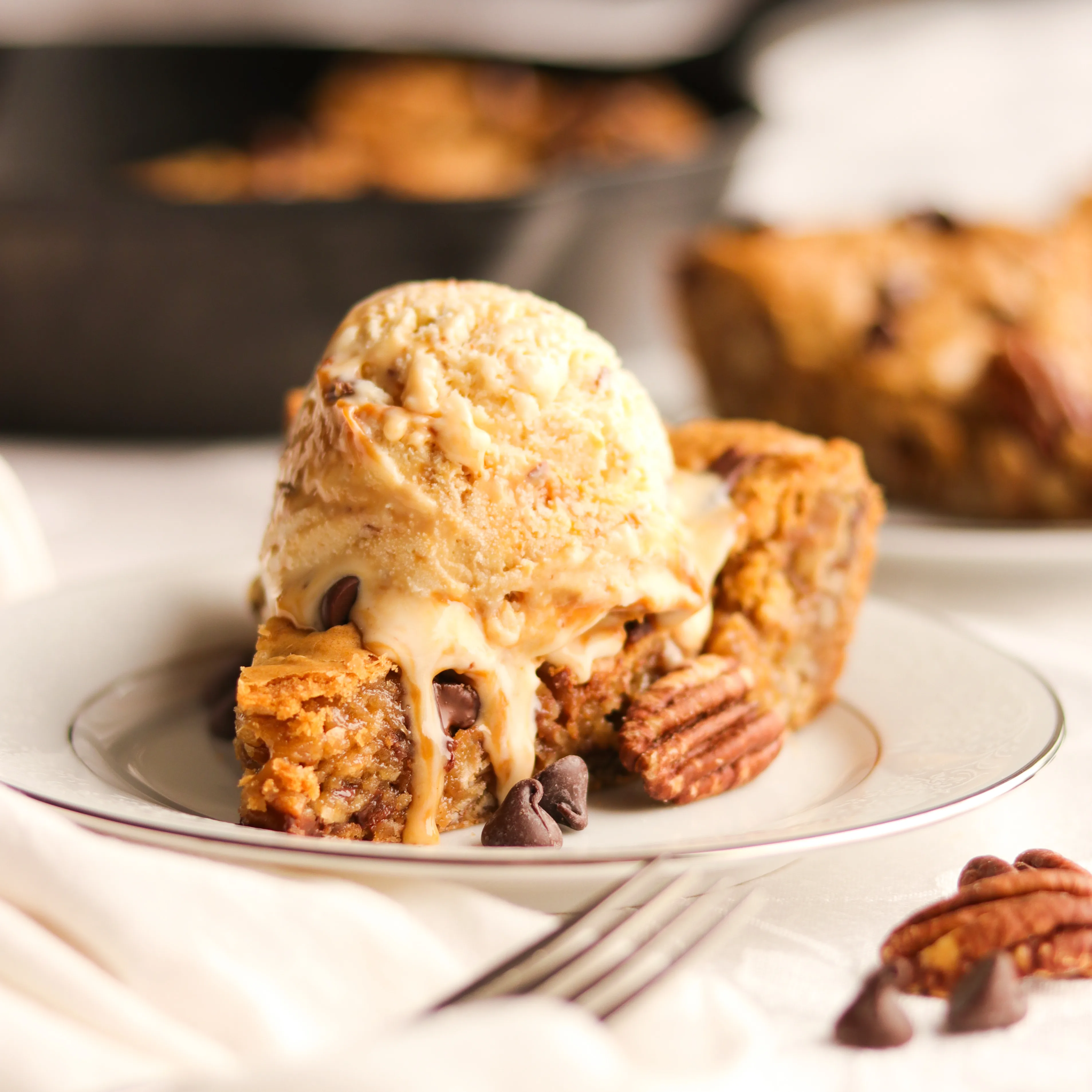 A warm and doughy deep-dish oatmeal cookie brimming with buttered pecans, chocolate chips, and chewy oats!