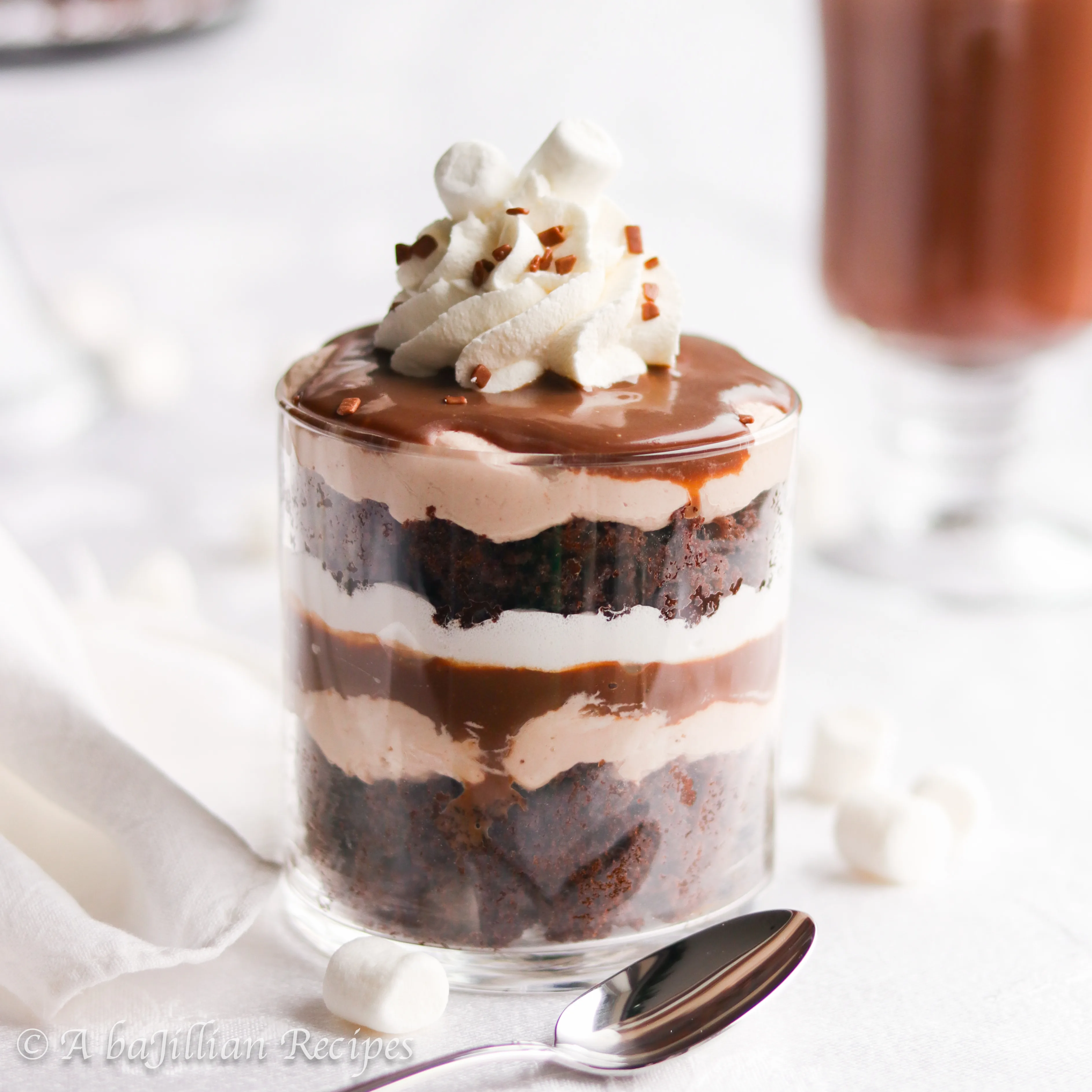 Pillowy cubes of chocolate cake, delicious hot chocolate cream filling, heavenly homemade marshmallow fluff, and rich chocolate fudge sauce all layered together in one impressive trifle!