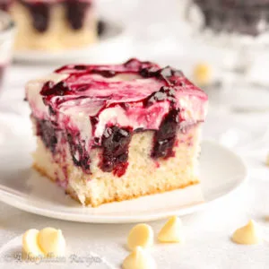 Delicate white cake, homemade blackberry topping, and lusciously creamy white chocolate topping--this White Chocolate Blackberry Poke Cake will have you licking every last crumb off your plate!
