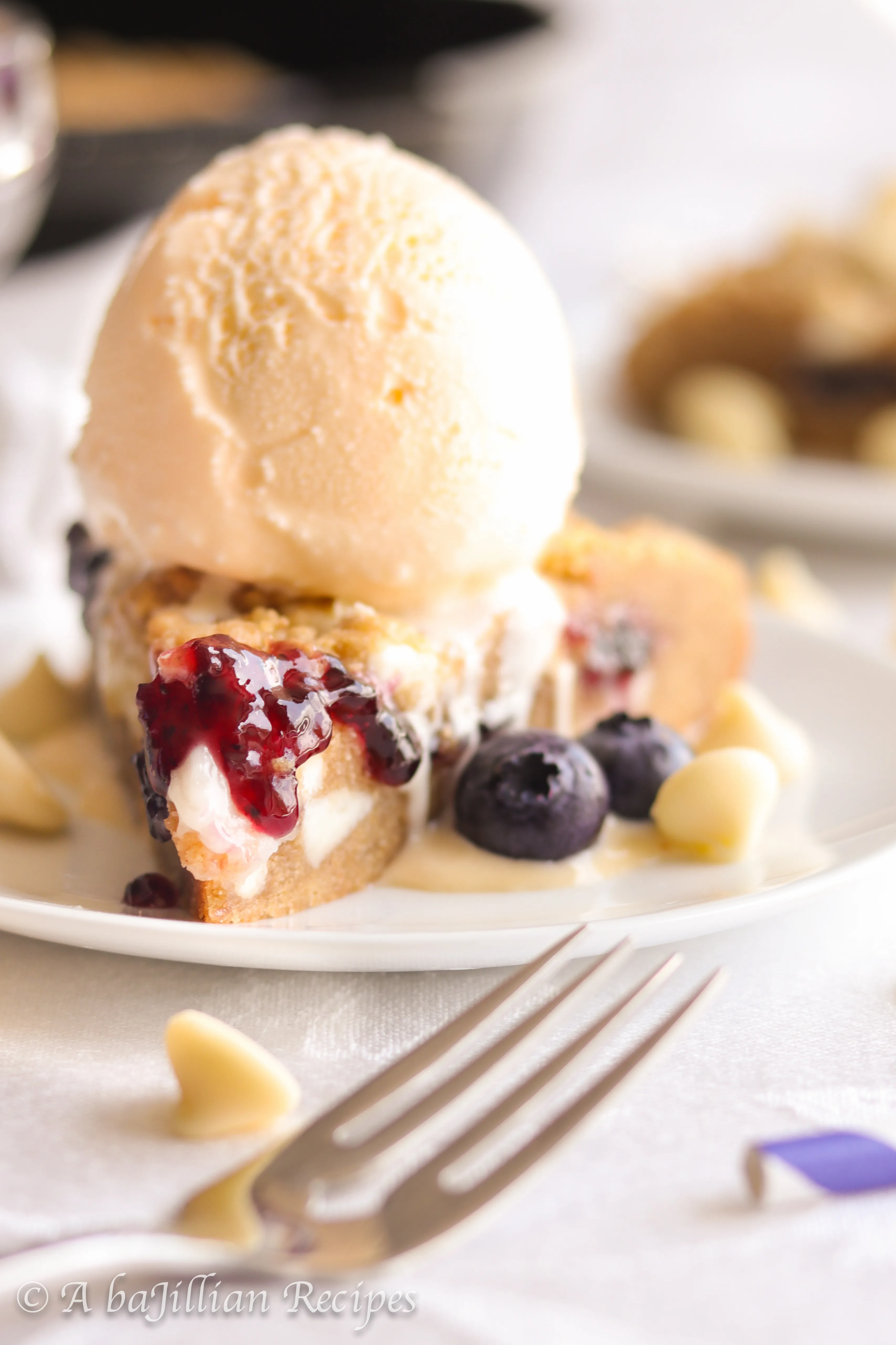 A warm, soft, and deliciously doughy graham-flavored cookie brimming with melty white chocolate chips, pockets of blueberry jam and cream cheese filling!