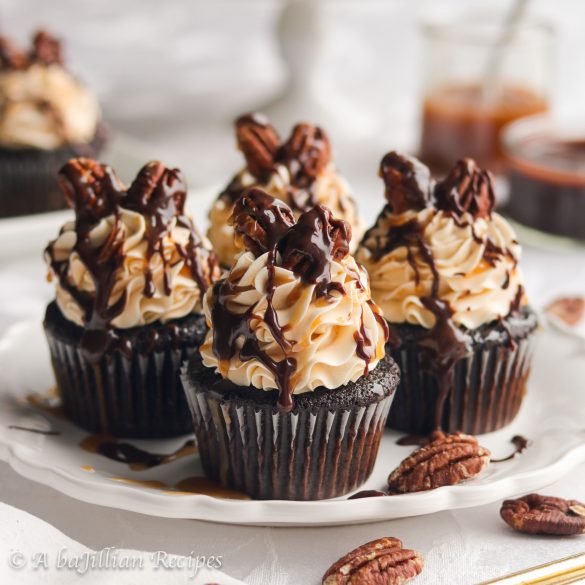 Moist chocolate cupcakes crowned with a silky smooth caramel Swiss meringue buttercream, topped with toasted pecans, and drizzled in both chocolate ganache and rich caramel!