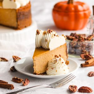 Tall, rich, and incredibly creamy, this Pumpkin Cheesecake is infused with warm spices, baked in a buttery Biscoff cookie crust, and crowned with fluffy cream cheese whipped cream!