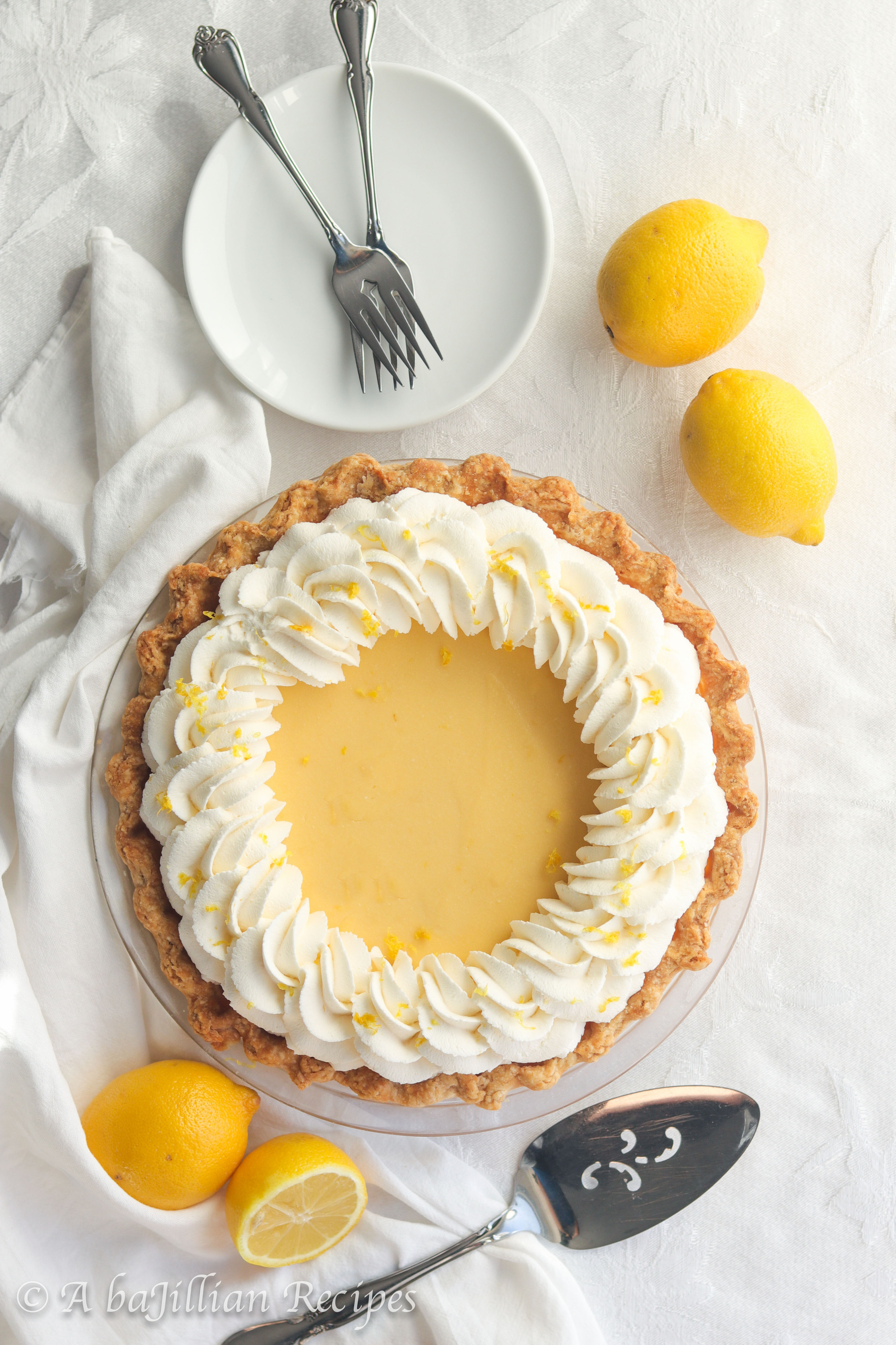 Smooth and creamy lemon filling nestled in a golden flaky pastry crust and crowned with a fluffy border of lemon-kissed whipped cream.